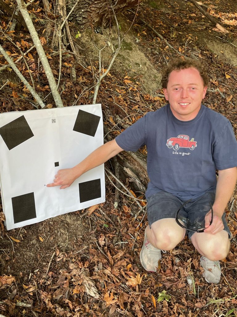 Matt pointing at a bullet hole down and left of center